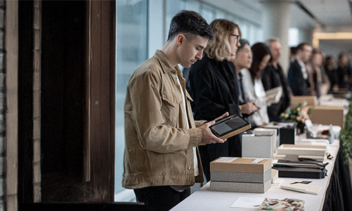 Visitors browsing printed works on a table at the exhibition